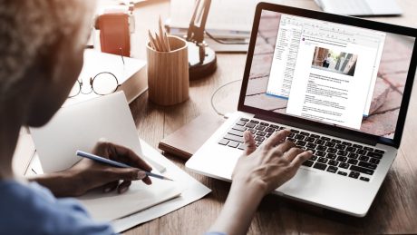 laptop, Woman typing with one hand, pencil in the left hand